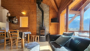 A cozy cabin interior with a stone fireplace, wooden furniture, and a view of the mountains. - 4-room apartment with Wifi and parking in Samoëns (Samoëns)