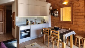 A compact kitchen with white cabinets, a built-in oven, and a dining area with wooden chairs and a table. - 4-room apartment with Wifi and parking in Samoëns (Samoëns)