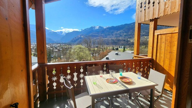 A wooden balcony with a table set for two, overlooking a mountainous landscape. - 4-room apartment with Wifi and parking in Samoëns (Samoëns)