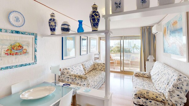 Un salón espacioso con una mesa de comedor de vidrio, sofás con estampado floral y un balcón con vistas.