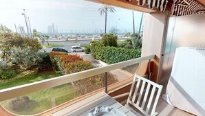 Un balcón con vista a un puerto deportivo y coches aparcados.