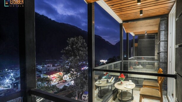 A modern hotel room with a large glass window offering a view of a city at night. - Vinsober Kainchi Dham Nainital  (Kosiyakutoli)