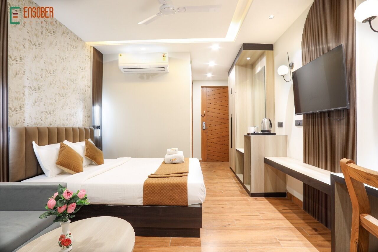 A hotel room with a bed, a TV, a desk, and a chair.