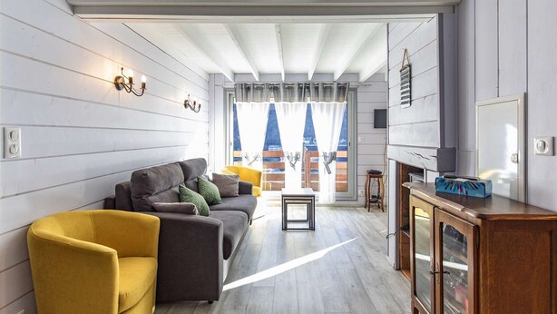 A modern living room with a sofa, a yellow armchair, and a wooden cabinet.