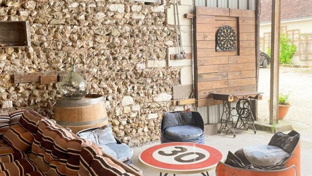 A rustic outdoor seating area with stone walls, a dartboard, and a speed limit sign. - Family cottage with private terrace near Beauval (Meusnes)