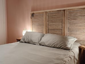 A bed with a wooden headboard and a bedside table with a lamp.