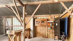 A rustic barn interior with wooden beams, a wooden cabinet, and a black grill. - Family cottage with private terrace near Beauval (Meusnes)