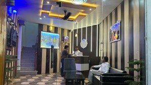 A reception area with a patterned floor, a reception desk, a seating area, and a wall-mounted TV. - Atithi Palace Luxury Guest House (Varanasi)