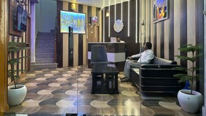A hotel lobby with a reception desk, seating area, and a staircase leading to the upper floor. - Atithi Palace Luxury Guest House (Varanasi)