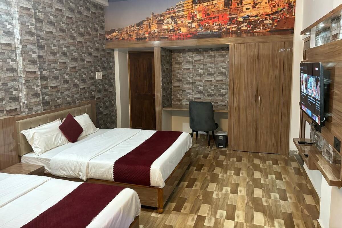 Habitación de hotel con dos camas, un escritorio, un televisor y un mural de un paisaje urbano en la pared.