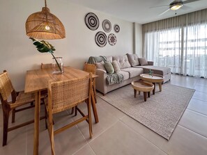 A modern living room with a dining area, a sofa, a ceiling fan, and decorative wall art.