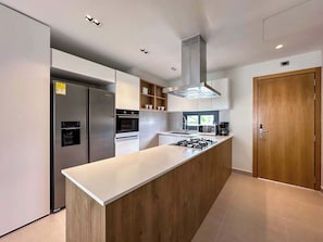 A modern kitchen with a central island, built-in appliances, and a wooden door.