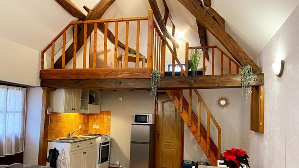 A cozy kitchen with a wooden staircase, a dining area with a table and chairs, and a living room with a sofa. - Charming house for 4 people in Tour-en-Sologne, with air conditioning (Tour-en-Sologne)