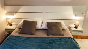 A neatly made bed with a teal blanket, two brown pillows, and two bedside lamps on nightstands. - Charming house for 4 people in Tour-en-Sologne, with air conditioning (Tour-en-Sologne)