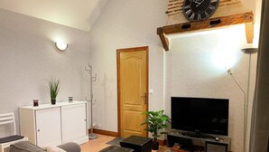 A modern living room with a sofa, a television, a cabinet, and a plant. - Charming house for 4 people in Tour-en-Sologne, with air conditioning (Tour-en-Sologne)