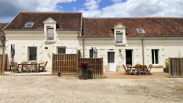 A two-story building with a tiled roof, a wooden fence, and outdoor seating. - Comfortable cottages near Beauval with wifi and parking (Meusnes)
