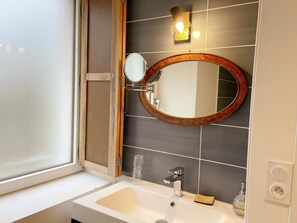 A bathroom with a white sink, a mirror with a wooden frame, a towel, and a soap dispenser. - The Ronsard Mill: Spacious house, garden, and Loir view - 8 people (Vallée-de-Ronsard)
