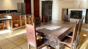 Une cuisine spacieuse avec une grande table à manger, des chaises en bois et un four encastré.