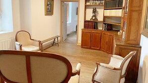 Une pièce spacieuse avec un meuble en bois, deux chaises, un banc et une bibliothèque remplie de livres.