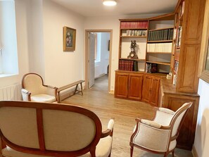 A spacious room with a wooden cabinet, two chairs, a bench, and a bookshelf filled with books. - The Ronsard Mill: Spacious house, garden, and Loir view - 8 people (Vallée-de-Ronsard)