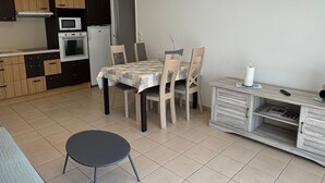 A compact kitchen with a dining area, a small table, and a single chair.