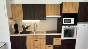 A compact kitchen with a microwave, oven, and a coffee maker on the countertop.