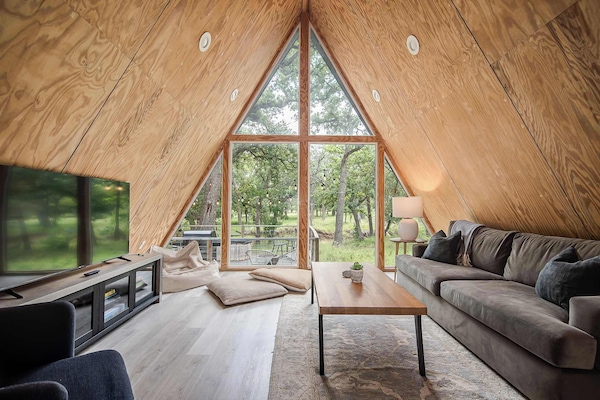 Soak in serene, hill country views through the floor-to-ceiling windows in the living room - complete with a smart TV and soft, oversized sofa.