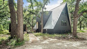 A cabin with a sloped roof, surrounded by trees, and a wooden pathway leading to it. - Large A-Frame in Nature - minutes from Main (Fredericksburg)