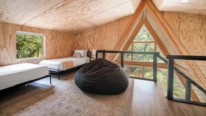 A wooden interior with a loft bed, a bean bag, and a view of trees through large windows. - Large A-Frame in Nature - minutes from Main (Fredericksburg)