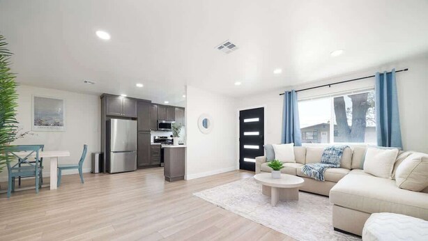 A modern living room with a beige sofa, a dining table with chairs, and a kitchen area with a refrigerator and cabinets. - 4 Miles to Beach Central and Newly Renovated (San Diego)