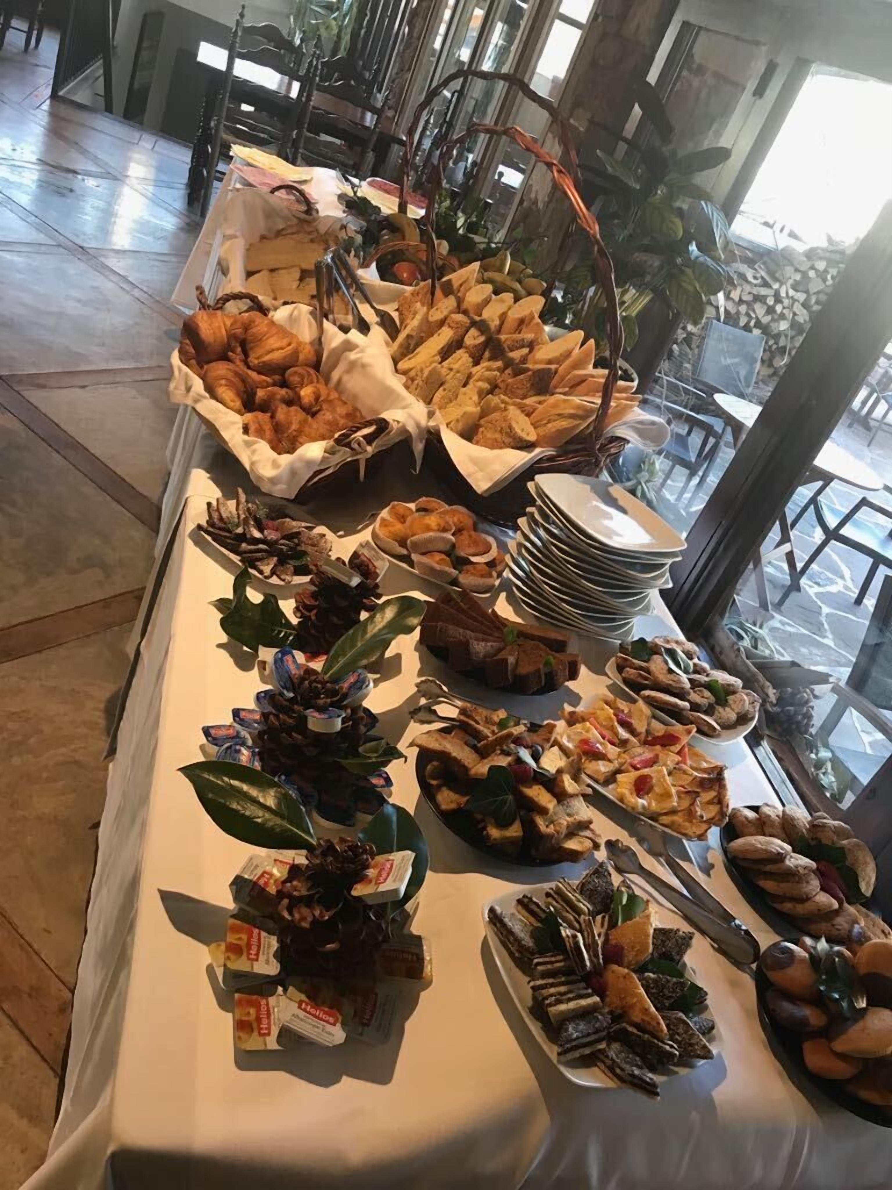 Una mesa de buffet con diversos alimentos, como pan, pasteles y sándwiches.
