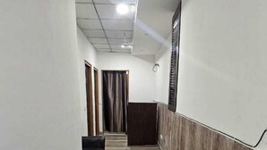 A hallway with a wooden floor, white walls, and a ceiling with recessed lighting. - THE OCEAN (New Delhi)