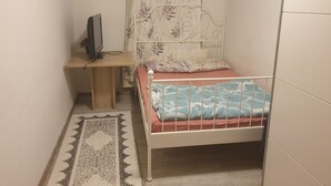 Un dormitorio pequeño y ordenado con una cama individual, un escritorio y una silla.