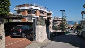 A residential building with multiple balconies, a parking area, and a view of the sea. - Casa Marta With Garden and hot tub (Formia)