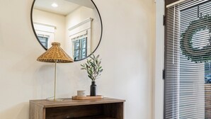 Una consola de madera con un espejo, una lámpara y un florero con plantas.