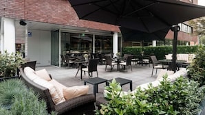 Un patio al aire libre con muebles de mimbre, mesas y sombrillas.