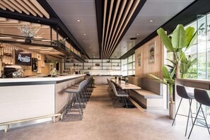 A modern restaurant with a long counter, bar seating, and a high ceiling with linear lighting. - Executive Residency by Best Western Amsterdam Airport (Hoofddorp)