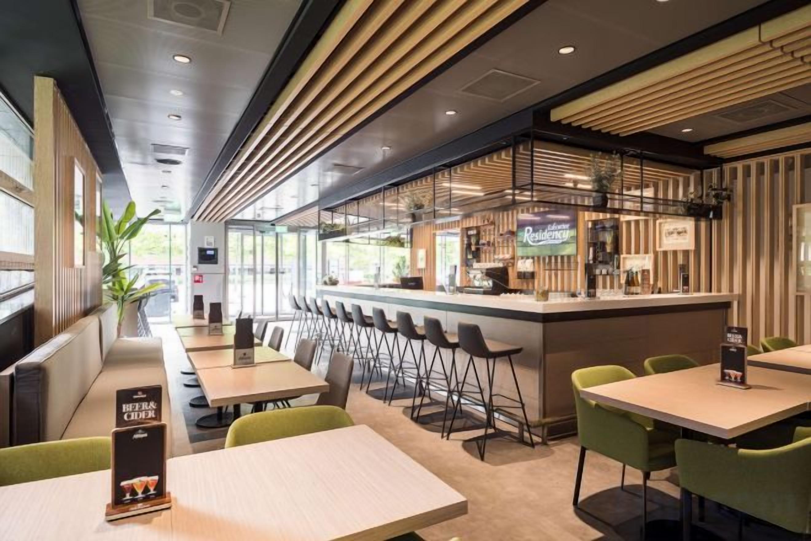 Un restaurant doté d’un bar, de plusieurs types de sièges, notamment des tabourets hauts et des tables, et d’un décor intérieur moderne.