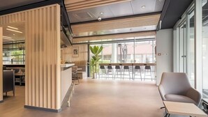 Un interior moderno con mostrador de recepción, zona de estar y ventanas amplias.