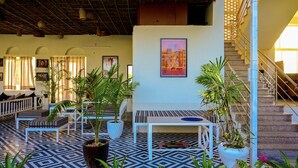 A hotel lobby with a patterned floor, white furniture, potted plants, and a staircase. - Hari Om Tatsat Retreat Pushkar (Pushkar)