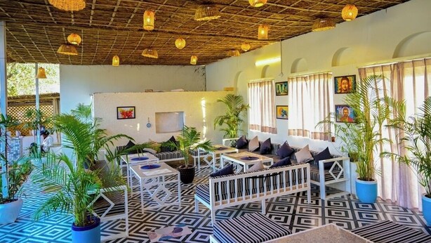 An indoor seating area with patterned flooring, white furniture, and hanging lanterns. - Hari Om Tatsat Retreat Pushkar (Pushkar)