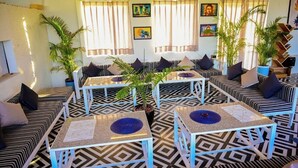 A modern lounge area with striped sofas, small tables, and potted plants. - Hari Om Tatsat Retreat Pushkar (Pushkar)