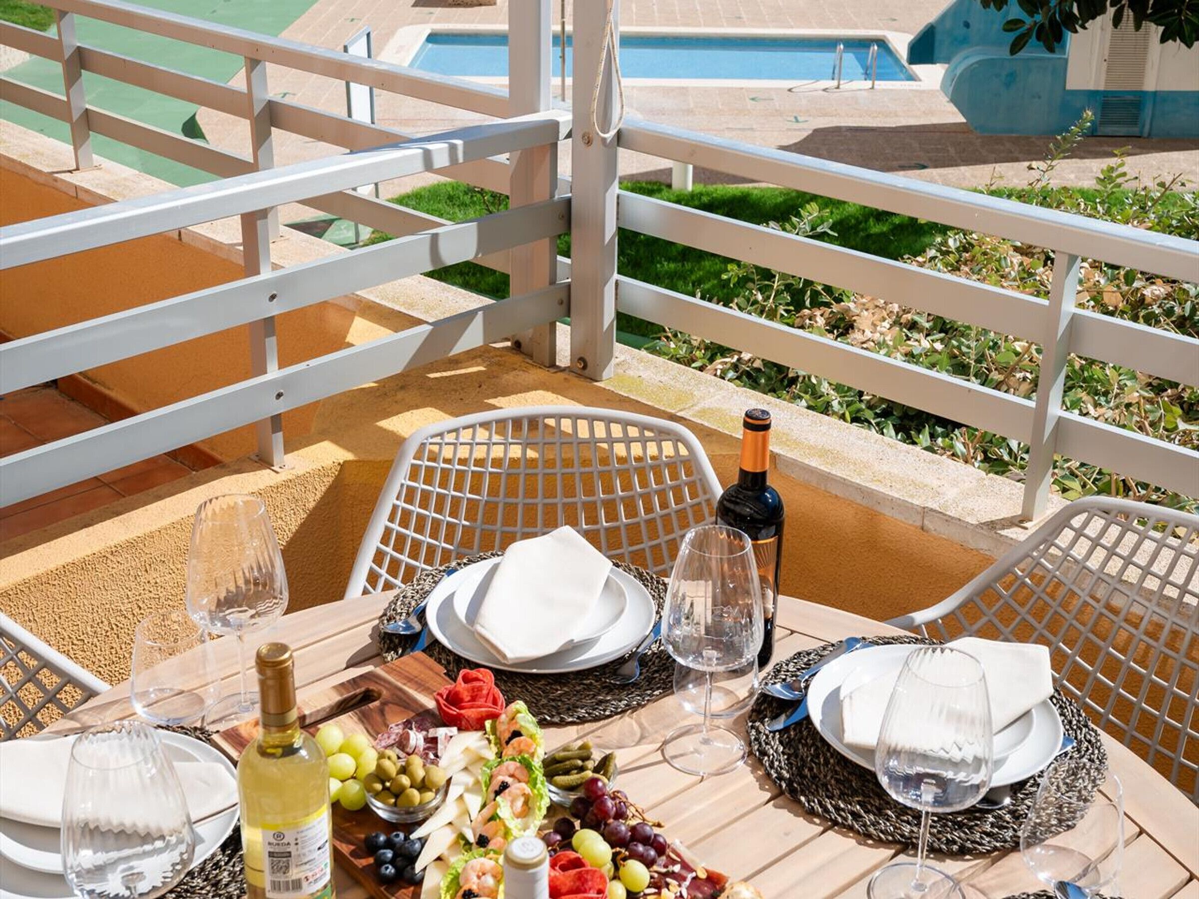 Une table dressée pour un repas, avec vue sur une piscine et un espace verdoyant.
