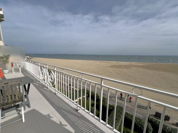 A balcony with a view of a beach and the sea.