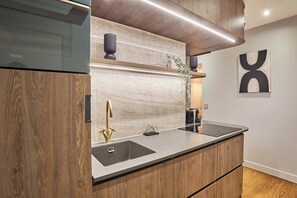A modern kitchen with a built-in oven, a stainless steel sink, and a coffee machine. - Sublime AC Apartment - Champs Elysees (Paris)