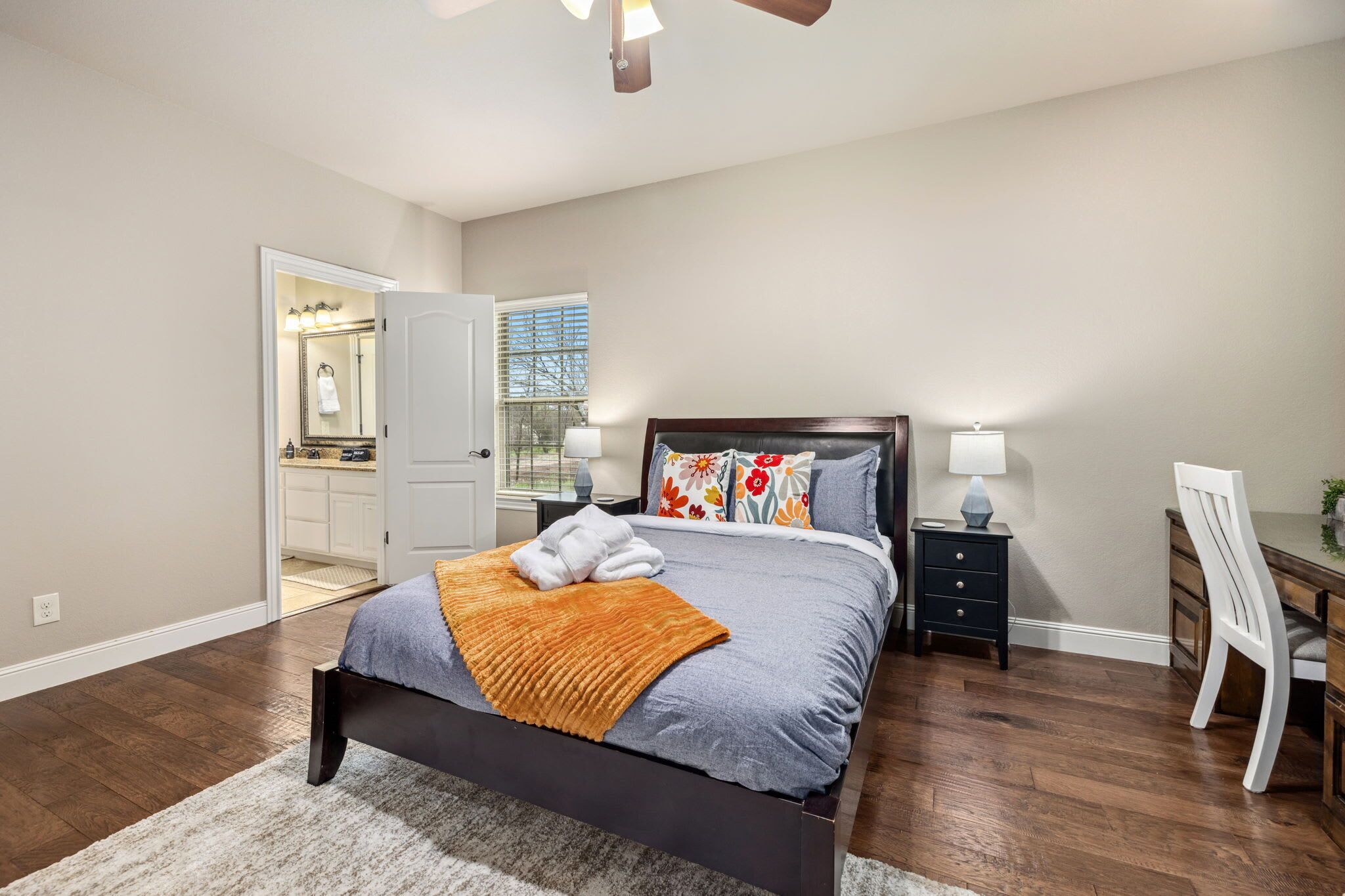 Une chambre à coucher comprenant un lit, des tables de chevet, un bureau et une chaise.