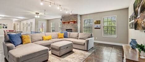 A spacious living room with a sectional sofa, a fireplace, and a large window.
