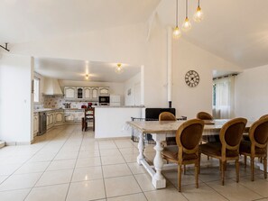 A spacious kitchen with white cabinets, a dining area with a marble table and wooden chairs, and a clock on the wall. - Quiet countryside cottage with pets allowed, parking and wifi (Rouans)
