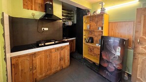 A compact kitchen with wooden cabinets, a gas stove, and a refrigerator. - Holiday Moods (Manali)