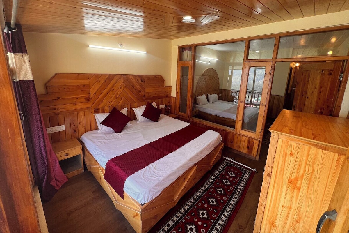 Una habitación de madera con una cama, un espejo y un mueble bajo.